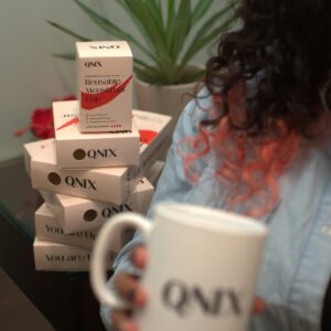 a woman holding a coffee mug in front of a stack of boxes