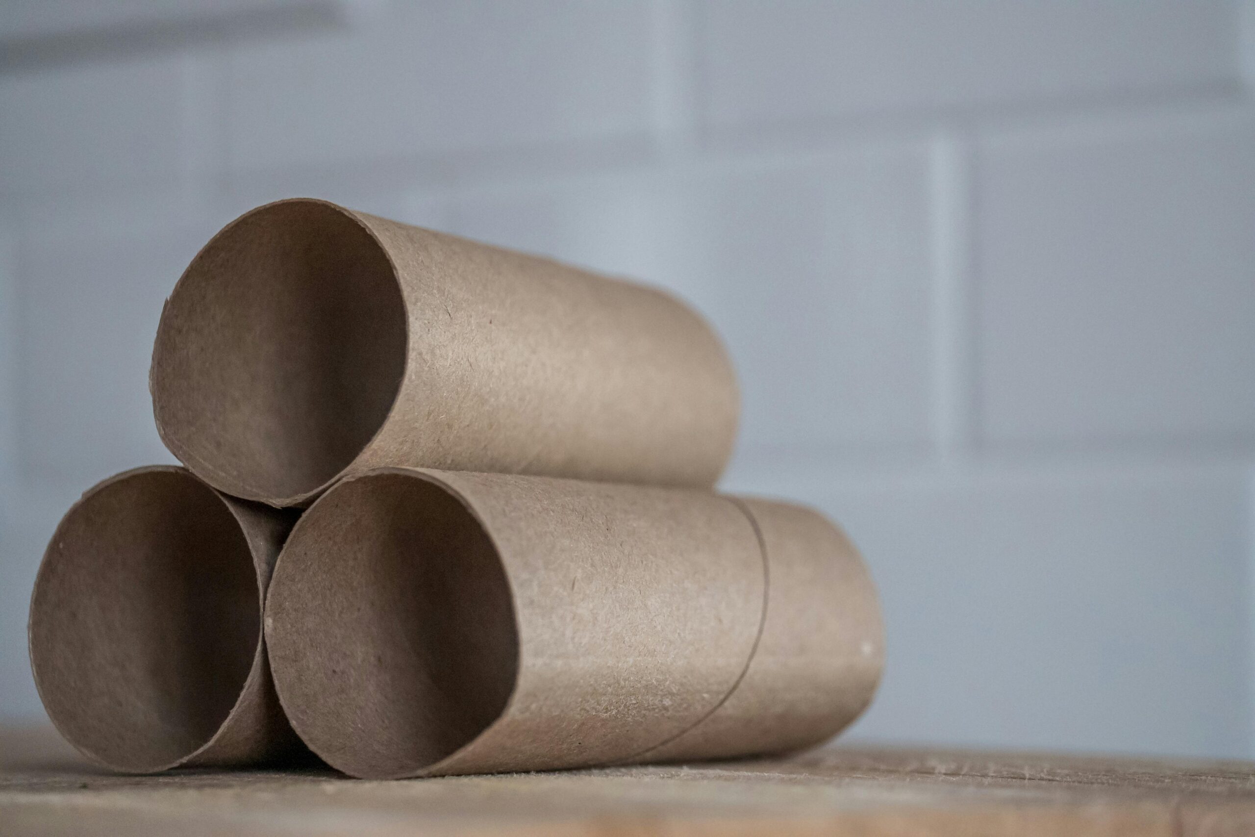 Closeup of stacked brown cardboard tubes of finished toilet paper placed on wooden table