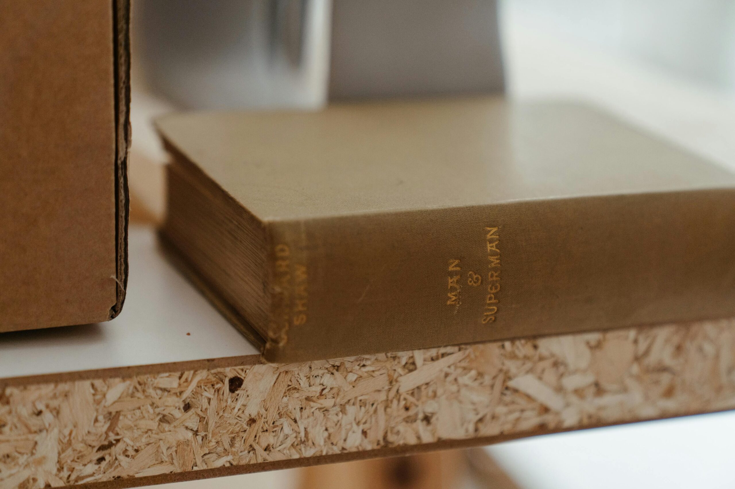 Close-up of a vintage book titled 'Man & Superman' placed on a wooden shelf indoors.