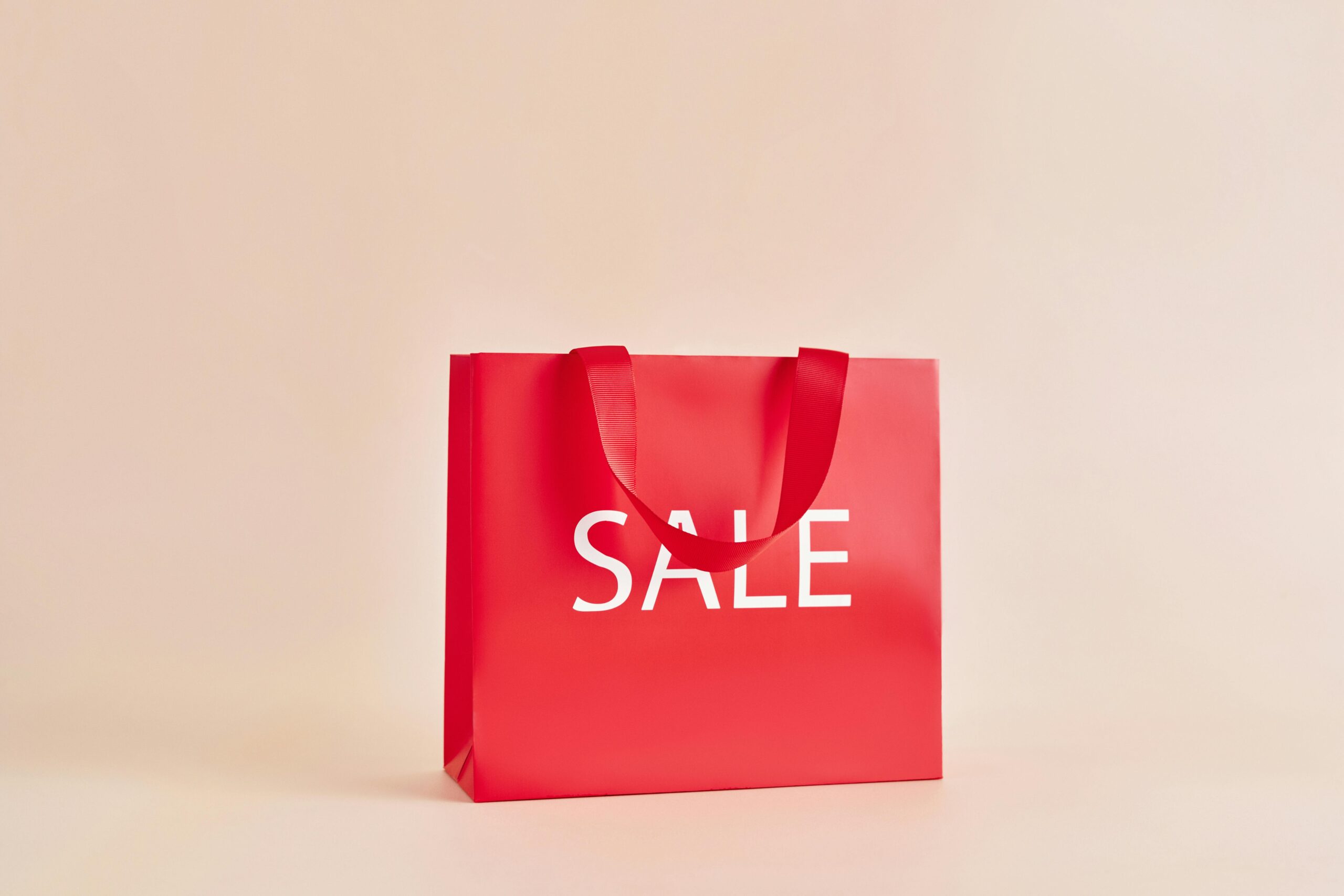 Minimalist image of a red sale bag on a neutral background, ideal for marketing.