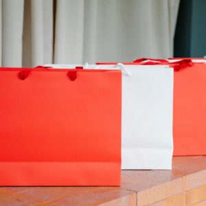 Set of red and white paper shopping bags placed on brick shelf in studio