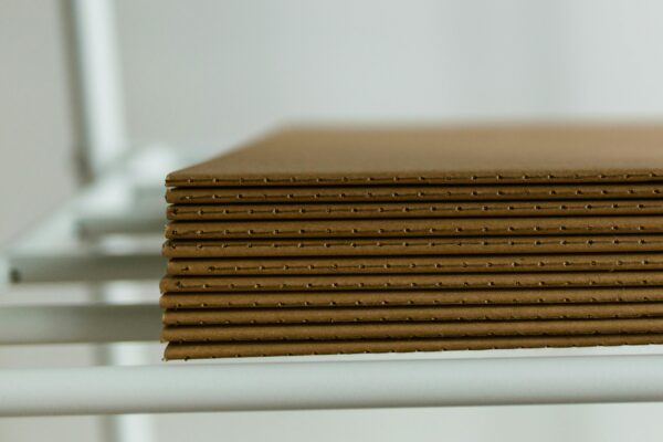 Close-up view of neatly arranged stacked cardboard sheets placed on a metal shelf, perfect for packaging concepts.